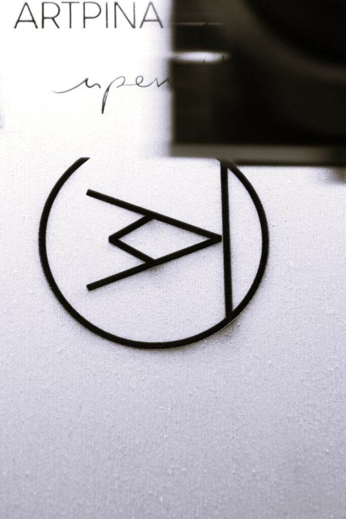 Vue du dessus de la gravure sur bois contreplaqué du logo Artpina, du nom et de la signature nperilli. La gravue se fait par un procédé de marquage laser.